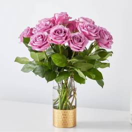 Pink roses arranged in a clear glass vase with a gold wrap