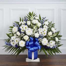 White daisies and roses in a blue ribboned vase arrangement