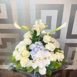 White floral arrangement with calla lilies, roses, hydrangea, and orchids