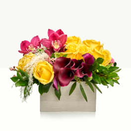 Yellow roses and magenta orchids in a rectangular vase
