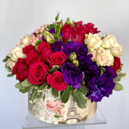 Bouquet of red, purple, and cream roses in a decorative box
