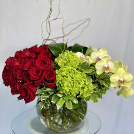 Red roses and green hydrangeas in a glass vase with pale orchids