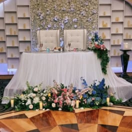Floral wedding stage with white draping and pastel arrangements