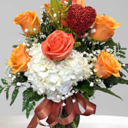 Bouquet of orange and coral roses with white hydrangea in a glass vase