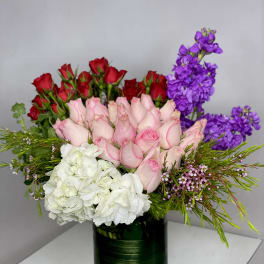 Mixed bouquet of pink and red roses with white hydrangeas and purple stock in a green vase