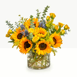 Sunflower bouquet with yellow roses in a glass vase