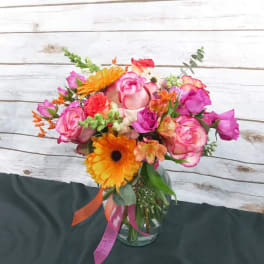 Colorful bouquet of pink roses and orange gerbera daisies in a glass vase