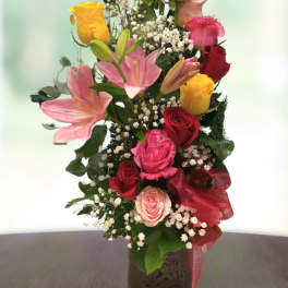 Mixed bouquet of roses and pink lilies in a square vase