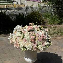 Large pastel rose arrangement in a white pedestal urn
