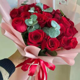 Bouquet of red roses with eucalyptus wrapped in pink paper