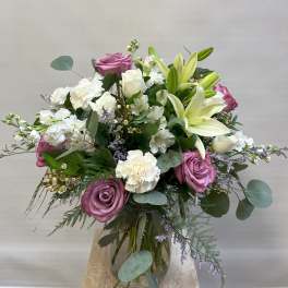 Bouquet of pink roses, white lilies, and white carnations in a glass vase