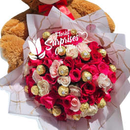 Teddy bear holding a bouquet of red and pink roses with chocolates