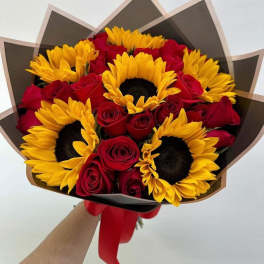 Bouquet of red roses and yellow sunflowers wrapped in dark paper