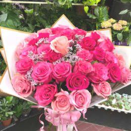 Large bouquet of pink and peach roses wrapped in white paper