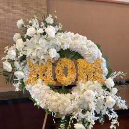 White and yellow floral wreath on an easel with large number 100
