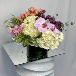 Pink roses, white hydrangeas, and lavender orchids in a black vase