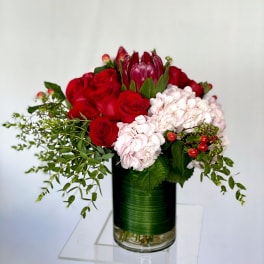 Red roses and pale pink hydrangeas in a glass vase