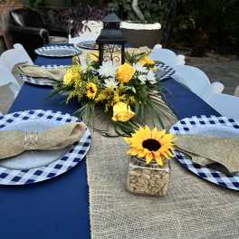 Yellow and white floral centerpiece with a lantern on a table