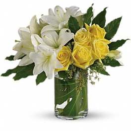 White lilies and yellow roses in a clear glass vase
