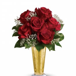 Arrangement of red roses with white filler flowers in a tall gold vase