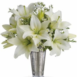 Tall silver vase filled with white lilies and small white blooms