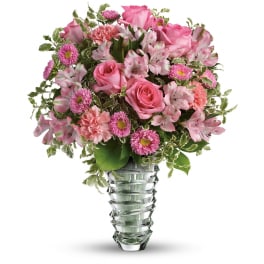 Pink roses, carnations, alstroemeria and asters arranged in a clear sculpted glass vase