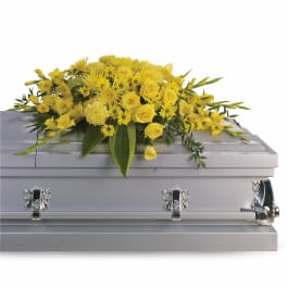Yellow rose and chrysanthemum casket spray on a closed light gray casket