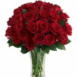Tall clear glass vase filled with a large bouquet of red roses.