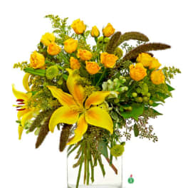 Tall arrangement of yellow lilies and spray roses in a clear glass cylinder vase.