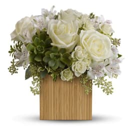 Compact arrangement of white roses, white blooms, and green succulents in a square wood container