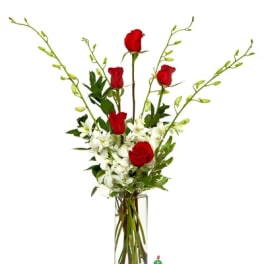 Tall clear vase with red roses and white orchids in a vertical arrangement