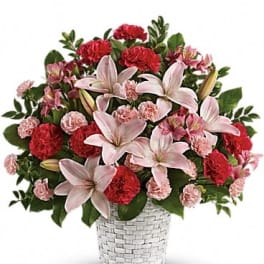 Pink lilies and red carnations in a white woven basket