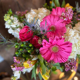 Mixed bouquet with bright pink gerbera daisies, roses, and white blooms in a clear vase
