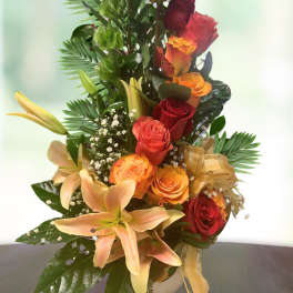 Tall bouquet of orange and red roses with lilies in a vase