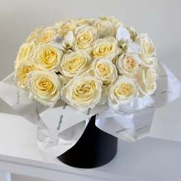 Bouquet of cream roses wrapped in white paper in a black box