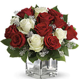 Red and white roses arranged in a clear square vase