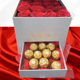 Open gift box with red roses and gold-wrapped chocolates