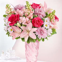 Pink mixed bouquet in a tall pink glass vase