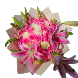Bouquet of pink roses, white roses, and pink lilies wrapped in pale paper.