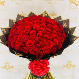 Large bouquet of red roses wrapped in black paper with a red bow