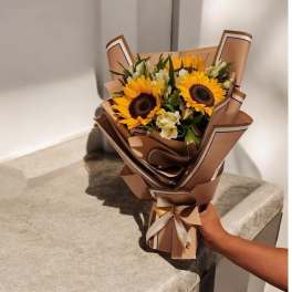 Bouquet of sunflowers and white flowers wrapped in brown paper