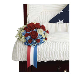 Red, white, and blue floral spray on a white-draped casket