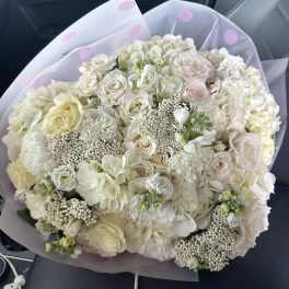 Large bouquet of white and blush roses with hydrangeas in lavender wrap