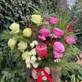 Hand-tied bouquet with pink, green, and white flowers and a red ribbon