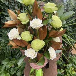 Bouquet of white roses and lime-green carnations with glossy foliage