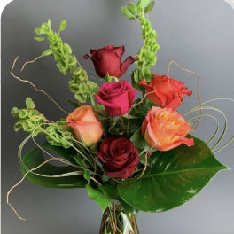 Mixed roses in a clear glass vase with curly greenery