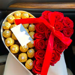 Heart-shaped box with red roses and gold-wrapped chocolates tied with a red ribbon
