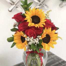 Bouquet of red roses and yellow sunflowers in a glass vase