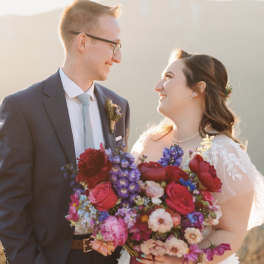Bride and groom holding a colorful wedding bouquet and boutonniere