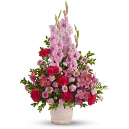 Tall pink and red mixed flower arrangement with gladiolus and carnations in a white woven basket